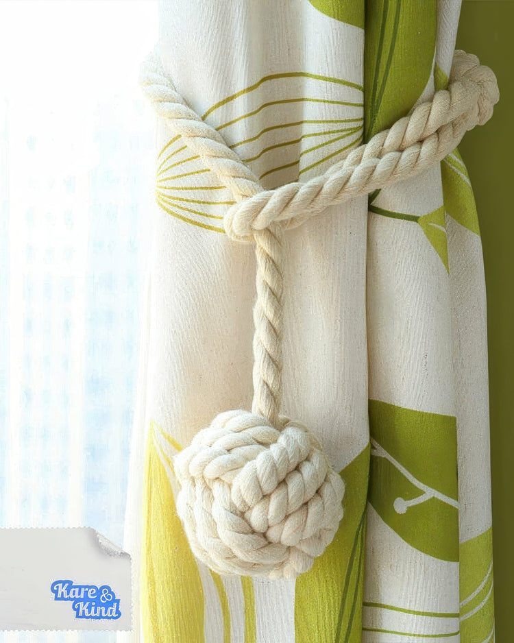 Chunky woven rope curtain tieback with a decorative ball knot securing a white custom drapery with a vibrant green leaf pattern.