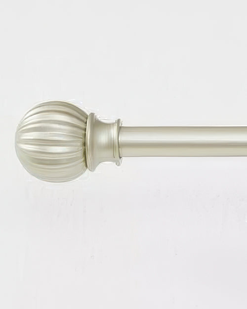 Detailed view of a brass adjustable curtain rod with a decorative ribbed finial for luxury window treatments.