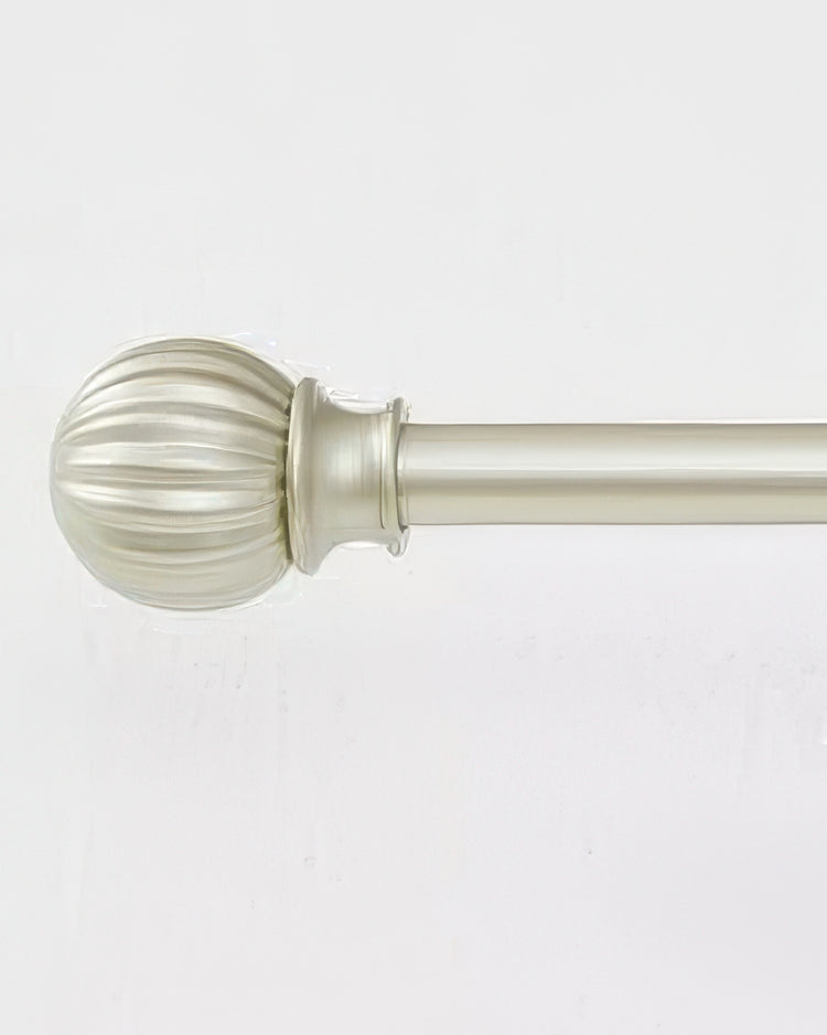 Detailed view of a brass adjustable curtain rod with a decorative ribbed finial for luxury window treatments.