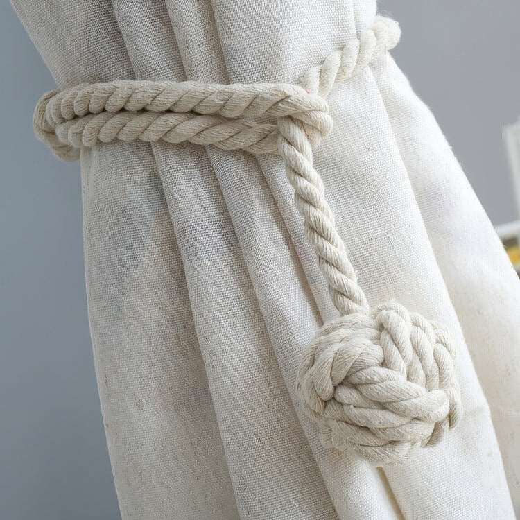 Thick braided rope woven ball curtain tieback holding back a textured cream linen drapery, adding custom home decor style.