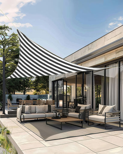 Black and white striped triangle sun shade sail covering a modern outdoor patio with beige sofa, armchairs, and dining set, providing UVShield protection.