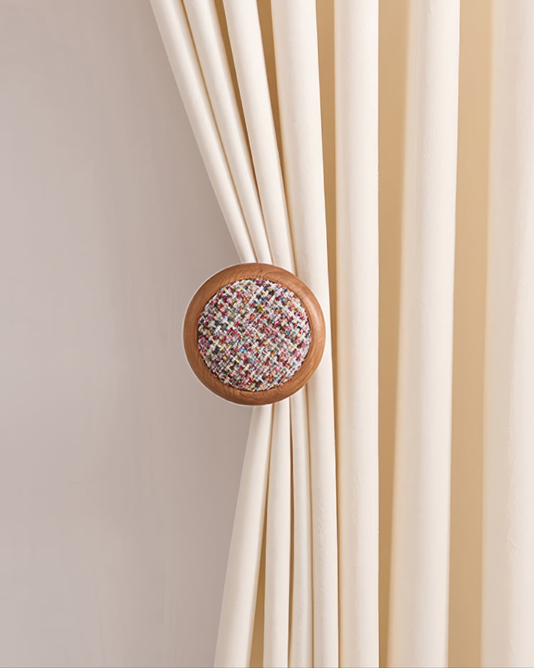 Elegant cream drapery secured by a sophisticated wooden curtain wall hook with colorful tweed yarn insert.