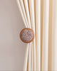 Elegant cream drapery secured by a sophisticated wooden curtain wall hook with colorful tweed yarn insert.