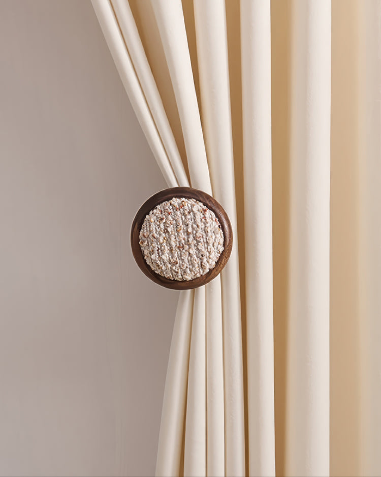 Cream curtain elegantly held back by a round, textured Coral Yarn Wooden Curtain Wall Hook.