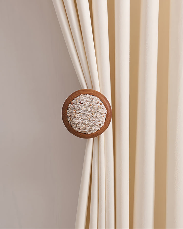 Round wooden curtain wall hook with coral yarn texture, elegantly tying back a cream custom drapery panel for refined window treatments.