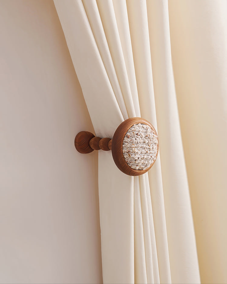 Coral yarn wooden curtain wall hook securing a cream drapery panel, perfect for custom window treatments.