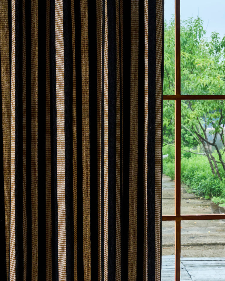 Close-up of Renee custom striped curtain with alternating vertical bands of black luxury velvet and textured golden linen fabric.