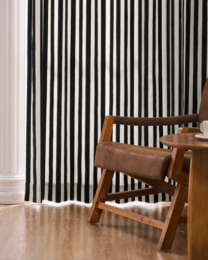 Stylish black & white striped linen blend custom curtain, perfectly paired with a brown leather armchair. Made-to-measure window treatment.
