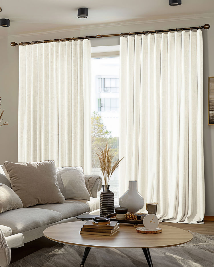 Cream Florence heavyweight 100% blackout custom drapery with a woven texture on a bronze rod, perfect for living room privacy.