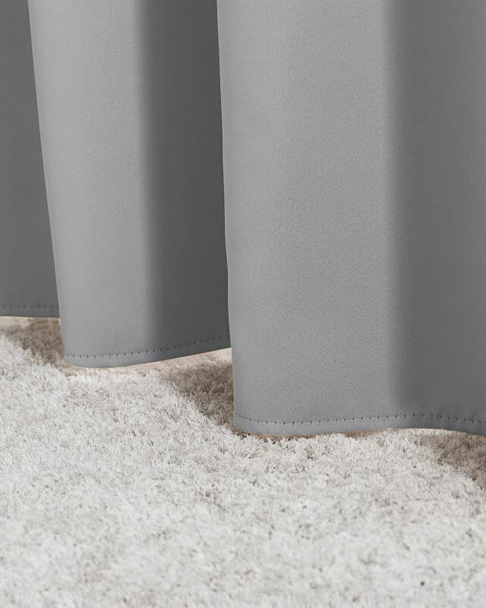 Bottom of gray Hussein OEKO Certified custom drapery panels gently touching a plush white rug, showcasing the quality hem.