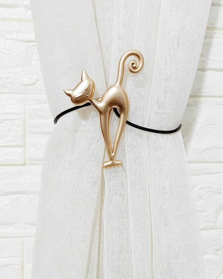 Stylized gold cat magnetic tieback securing a white sheer custom drapery panel. Elegant home decor for window treatments.