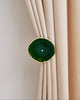 Elegant green natural crystal curtain wall hook securing a tailored beige velvet drapery for sophisticated home decor.