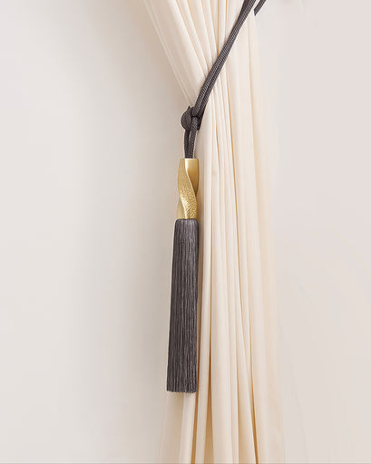 Luxury dark grey tassel tieback with twisted gold accent elegantly holding a cream custom drapery panel.