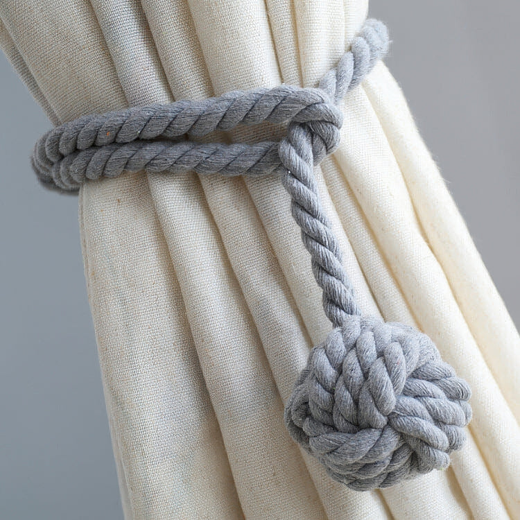 Elegant grey woven ball curtain tieback styling a custom cream pure linen drapery, enhancing sophisticated window treatments.