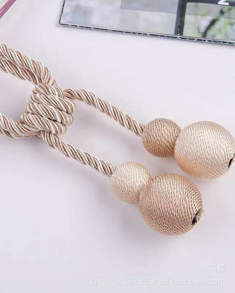 Elegant twisted beige & gold rope curtain tieback with two textured spherical tassels for luxury drapery.