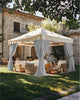 Lightweight, fade-resistant custom gray outdoor curtains tied back on a cream gazebo, defining a luxurious outdoor living area.
