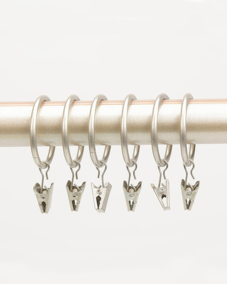 Six rustproof silver metal clip hooks on a champagne curtain rod, ideal for custom drapery and elegant window treatments.