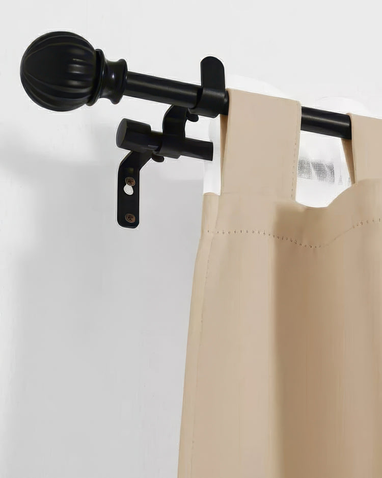 Close-up of black adjustable double curtain rod with decorative ball finial supporting beige custom drapery panels.