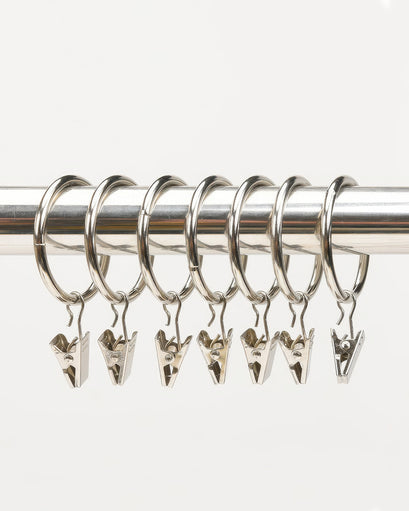 Seven rustproof metal curtain clip hooks on a silver drapery rod for custom window treatments.