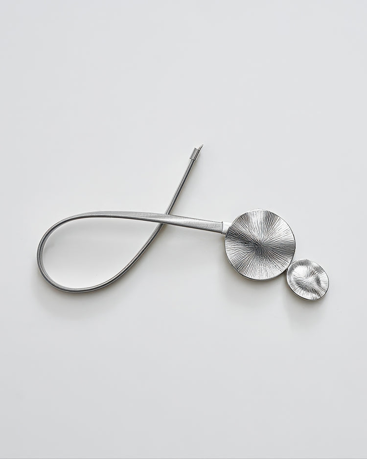 Silver springed curtain tieback with two textured round decorative discs for elegant drapery and window treatments.