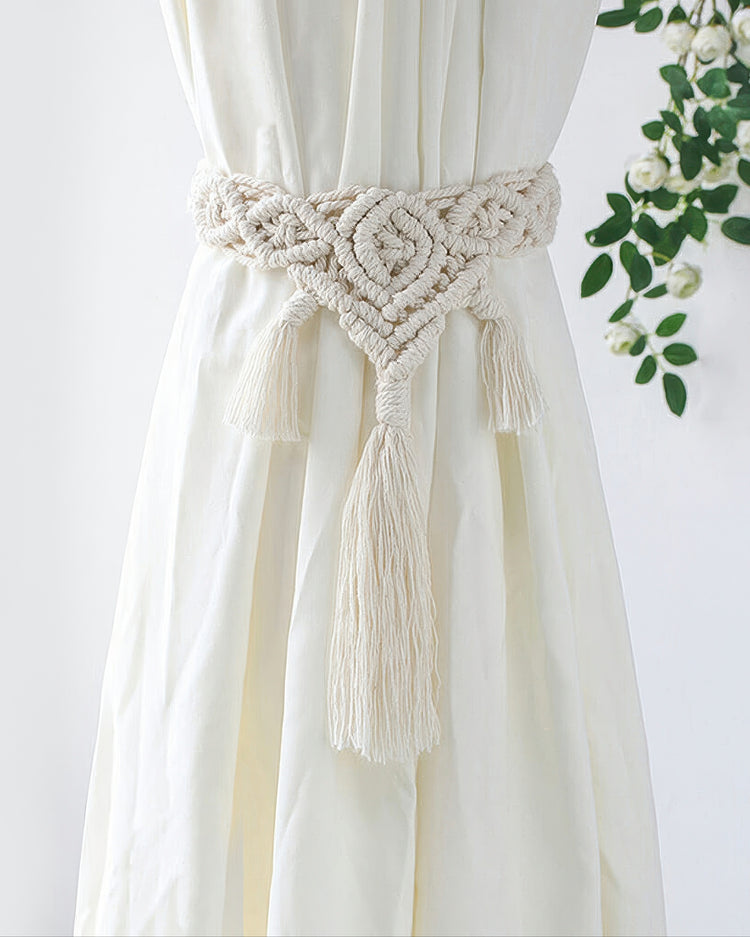 Hand-knotted cream macrame tassel curtain tieback with intricate bohemian pattern, securing a white linen drapery panel.