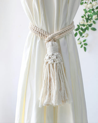 Natural cream macrame tassel curtain tieback featuring a twisted rope design, artfully cinching elegant custom drapery.