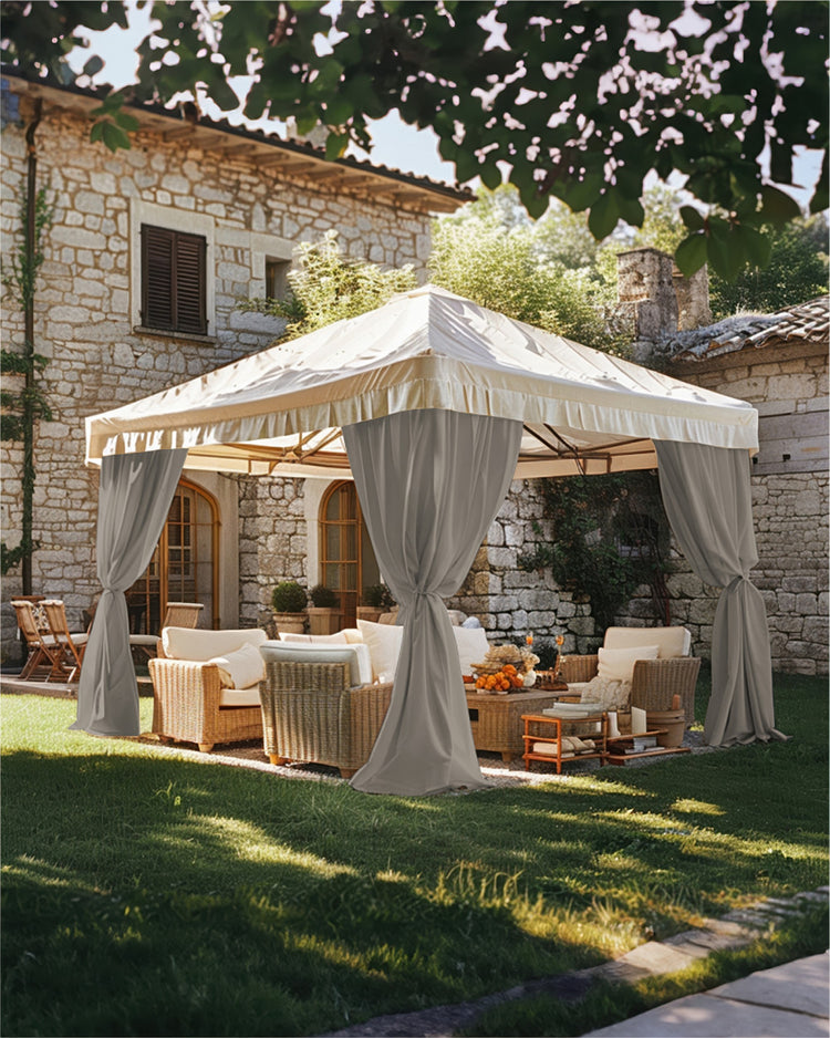 Elegant grey custom outdoor curtains tied back on a cream gazebo, creating a luxurious outdoor patio lounge with wicker furniture.