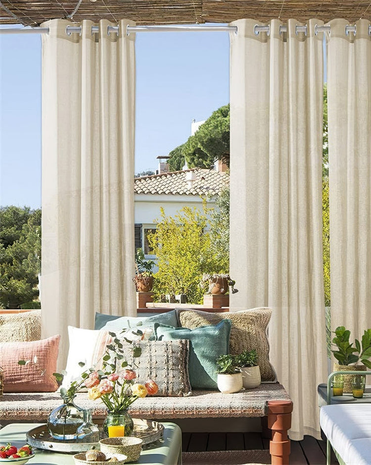 Cream custom linen look lightweight outdoor sheer curtains with grommet tops installed on a sunny patio, filtering light beautifully.
