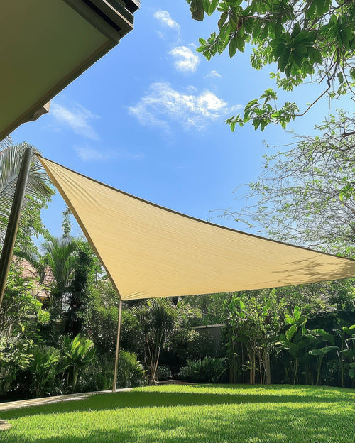 Custom beige waterproof triangle sun shade sail providing shade for a green outdoor patio area.