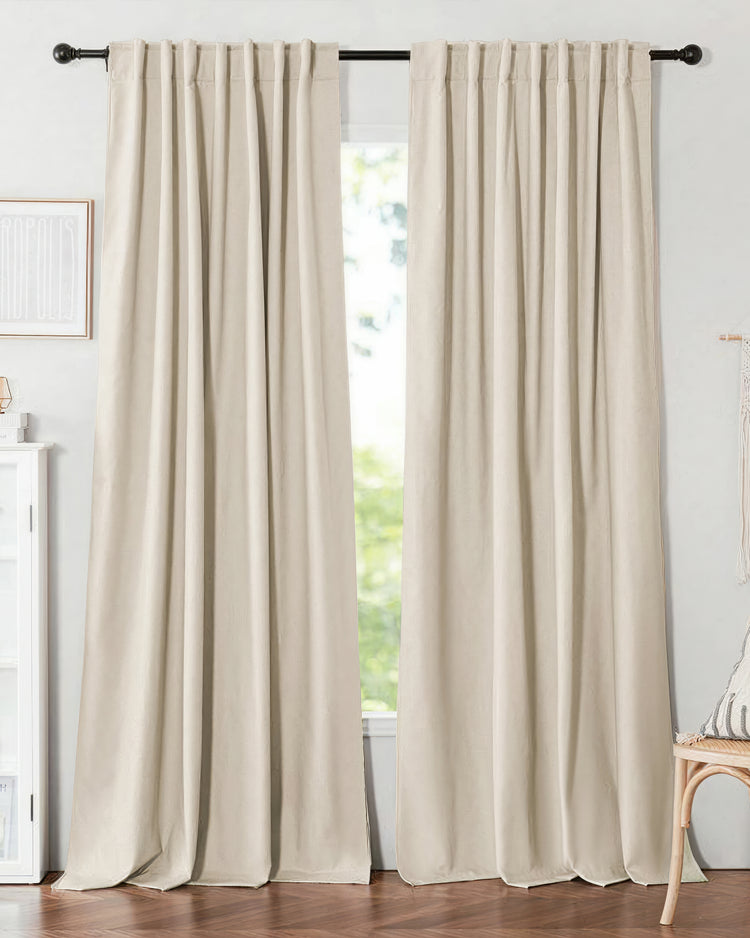 Elegant pair of custom linen-look beige blackout thermal drapery with back tab header, pooling beautifully on a wood floor.