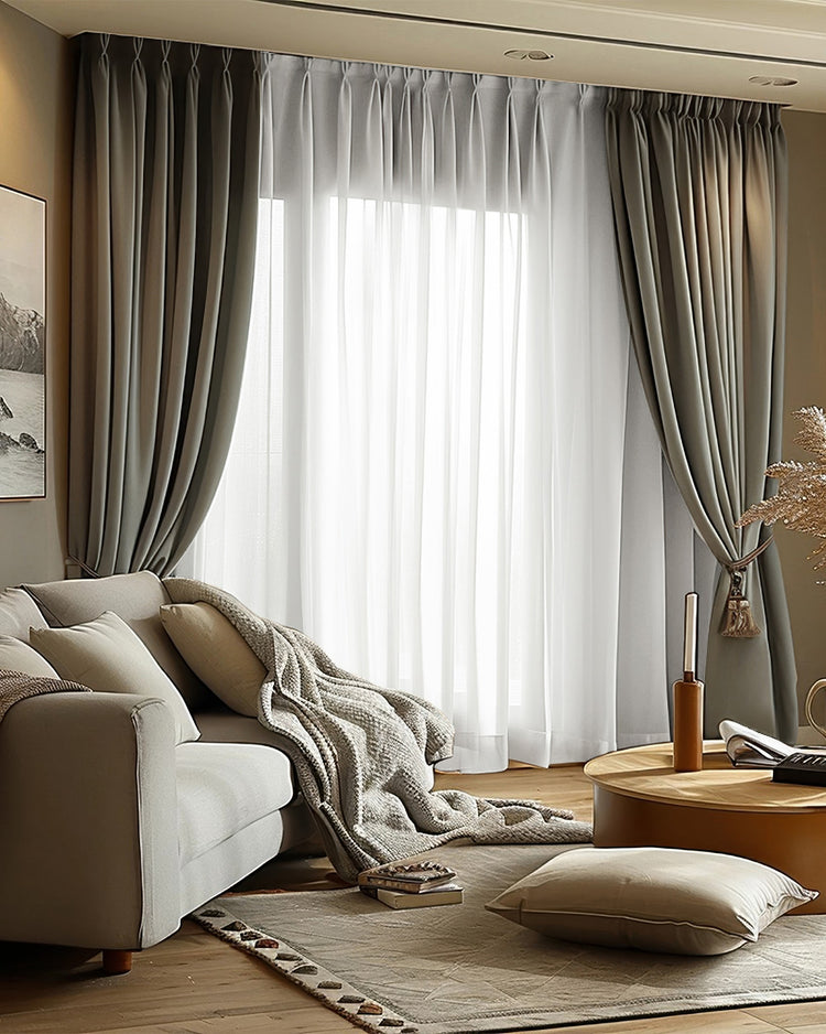 Victoria dark grey 100% blackout linen look custom pinch pleat drapery tied back, layered with white sheer curtains in a living room.