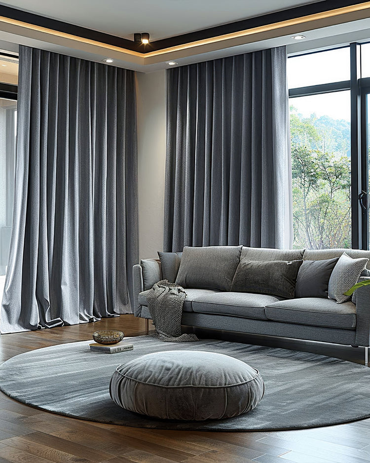 Custom grey velvet blackout curtains in a living room with a sofa, ensuring privacy & thermal comfort.