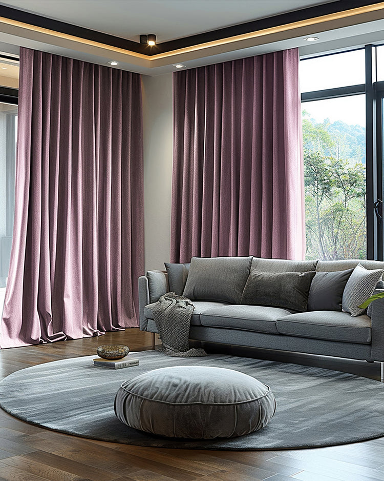 Luxury plum velvet custom blackout curtains framing large windows in a modern living room, with a gray sofa and greenery outside.