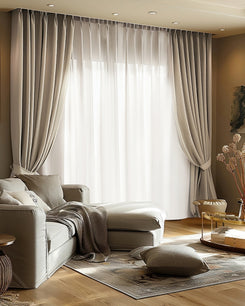 Custom beige blackout velvet curtains and sheer white drapery in a sunlit living room, offering elegant light control & privacy.