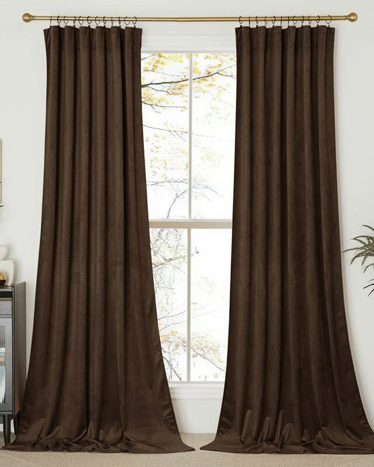 Classic brown velvet custom drapery panels with elegant pleats, full-length, framing a bright window on a brass rod.