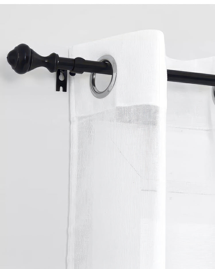 Close-up of black traditional adjustable curtain rod with decorative finial holding a white sheer grommet curtain.
