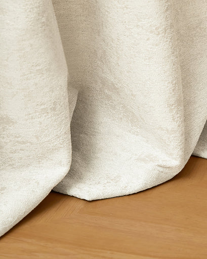 Soft, light cream Ambient Jacquard Custom Curtain fabric displaying its intricate woven texture and elegant drape on a wood floor.