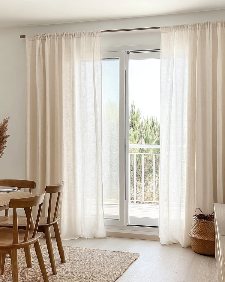 Light beige yarn linen look sheer custom curtains softening sunlight by a glass door, complementing modern home decor with wood.