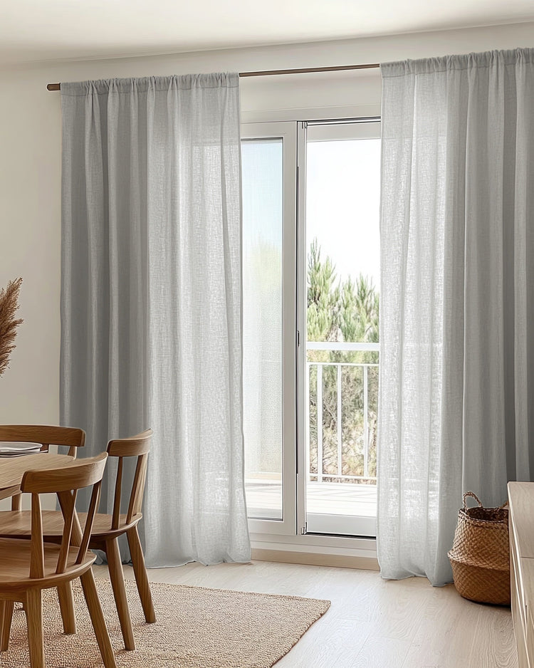 Light gray sheer linen look custom curtains with a rod pocket header on a glass patio door, enhancing light control & privacy.