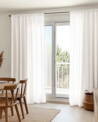 White custom yarn linen look sheer curtains with a gathered top, providing elegant light filtering over a large patio door.