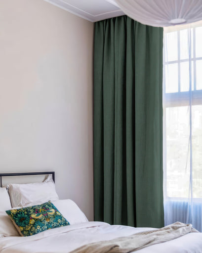 Bedroom with floor-length dark green 100% blackout custom curtain, linen look texture, beside sheer drapery.
