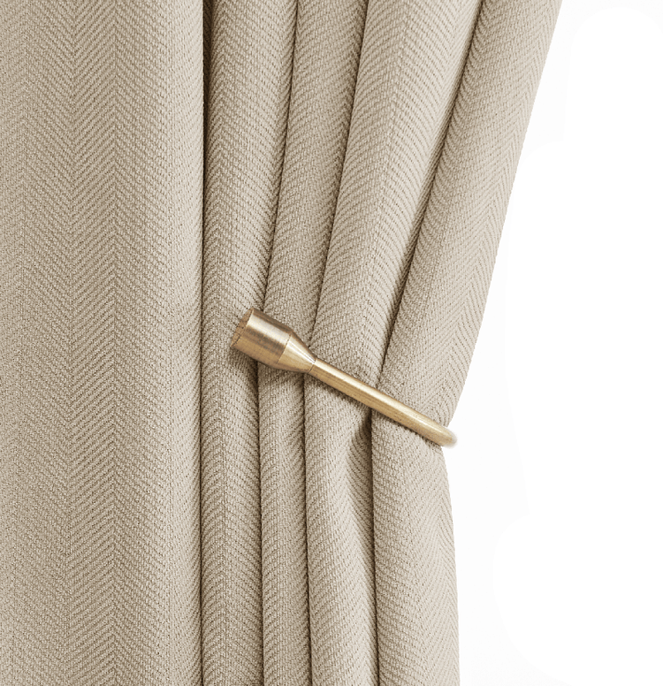 Bronze decorative curtain holdback securing a light beige custom drapery panel with a textured weave.
