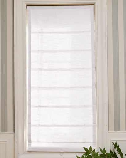 White Cassie Flat Fold Linen Blend Custom Roman Shade installed in a window, highlighting its clean lines and soft filtering of light.