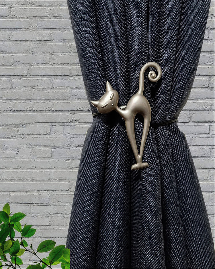 Elegant silver cat magnetic tie-back securing a textured dark blue custom drapery panel, enhancing window treatment decor.