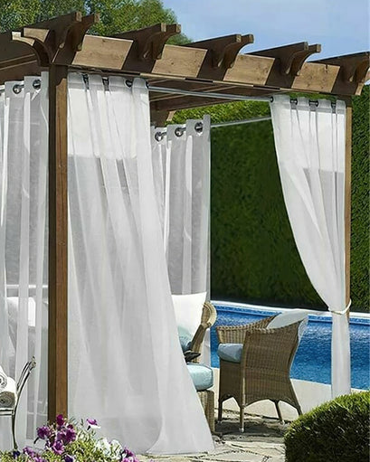 Elegant custom white sheer outdoor curtains with grommet headers on a wooden pergola, offering privacy for a pool patio.
