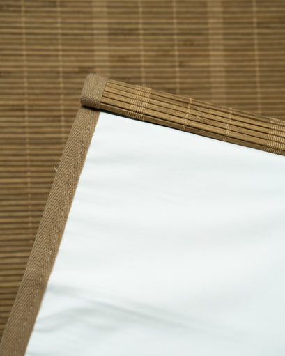 Close-up of tan Hana Bamboo Woven Shade with white privacy backing, showing natural bamboo slats and fabric trim.