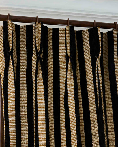 Custom Liam striped linen blend curtain in black & gold, featuring textured vertical stripes and a tailored pinch pleat header.