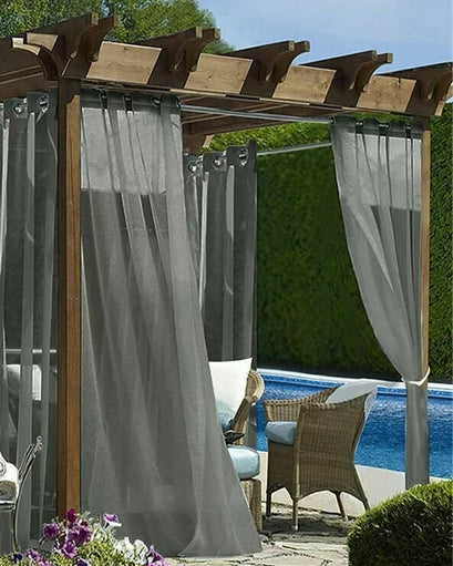 Grey Scottish custom outdoor sheer grommet curtains on a wooden pergola by a pool. Offers elegant made-to-measure privacy & light control.
