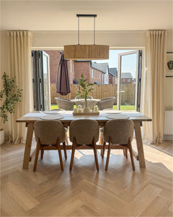 Sunveil linen sheer custom drapery with pleated header in a bright dining room, softly filtering natural light from large windows.