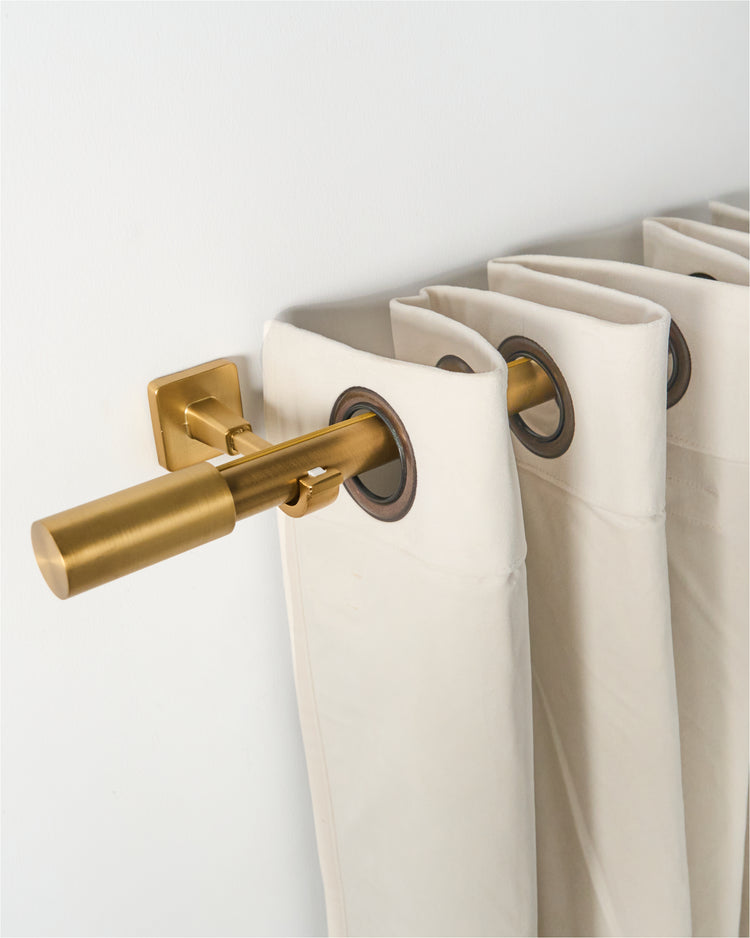 Silent Glide Roman Bronze curtain rod with square mount & cylindrical finial, holding cream grommet drapes for high-end window treatments.